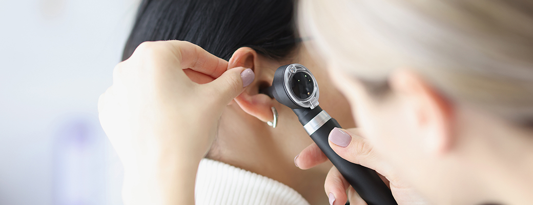 Close-up image of hearing care professional shining a light inside the ear of a female patient